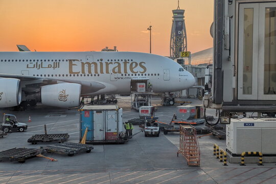 An Emirates Airbus A380 airplane undergoes cargo loading at Gate F9 at Dubai International Airport during a vibrant golden sunrise on December 14, 2023 in Dubai, UAE.