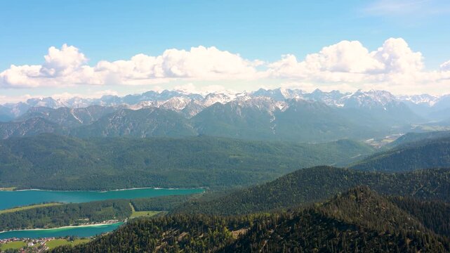 Scenic mountain panorama filmed from Heimgarten featuring Kochelsee, Kochel am See and the rugged peaks of the Bavarian Alps under summer skies.
