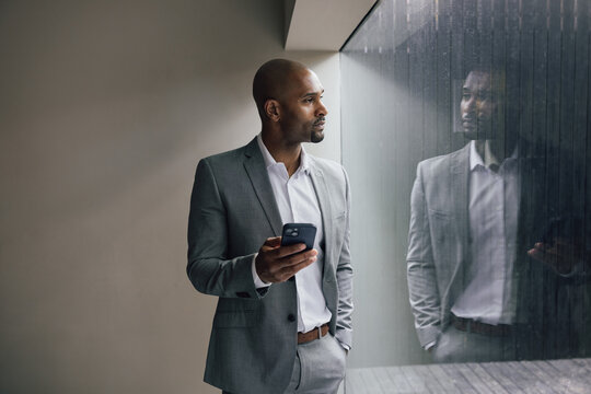 Man in a suit in thought while holding smartphone