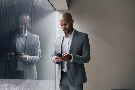 Businessman focused on smartphone near window