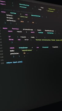 A modern computer monitor displays advanced code for a neural network. The dark mode text editor features vibrant syntax highlighting. An angled view highlights the active programming session.