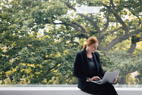 Woman Working on Laptop in Bright Office Space surrounded by nature