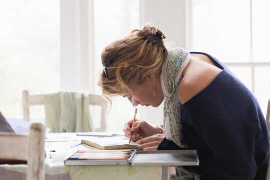 20 year old woman artist working on a drawing in her studio