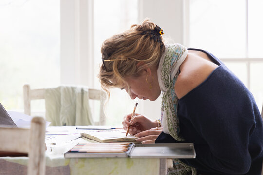20 year old woman artist working on a drawing in her studio