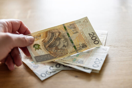 Plik banknot&oacute;w 200 złotych na dębowym stole &mdash; got&oacute;wka, bogactwo, wypłata, Polska