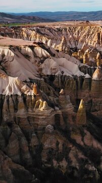 Aerial view of the iconic fairy chimneys of Love Valley in Cappadocia, Turkey. Unique rock formations sculpted by erosion rise from the volcanic landscape.