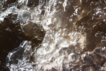 Dynamic motion of turbulent water in a spring creek, capturing the raw energy of thawing nature in detailed splashes and frothy cascades © PhotoChur