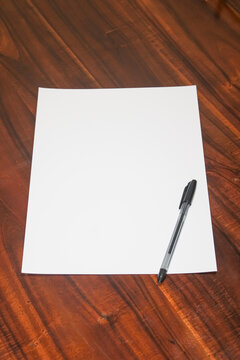 Blank white paper sheet with black pen on wooden table