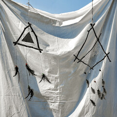 Handmade dreamcatchers with feathers hanging on white fabric © Aleksandr Bushkov