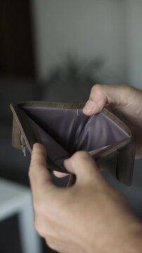 Empty wallet in hands symbolizing debt, poverty, financial hardship, budgeting and economic stress.