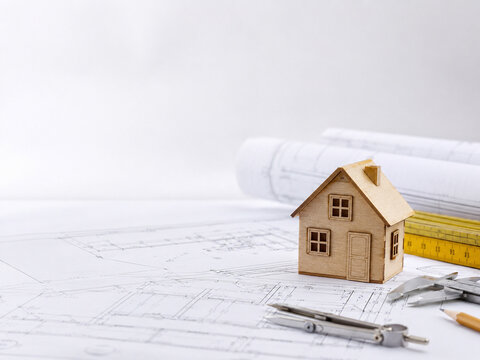 Wooden Model House on Blueprints with Drafting Tools