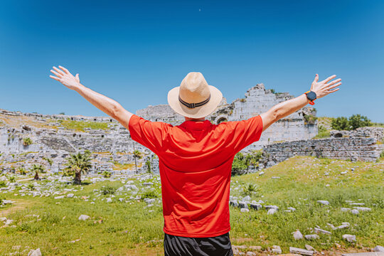 Traveler raising arms, enjoying freedom and exploration at the ancient ruins of Miletus on a sunny day
