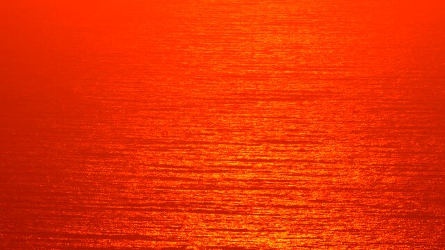 Sunset ocean water texture, deep red orange reflection background, abstract summer sea surface motion, vibrant color grading.