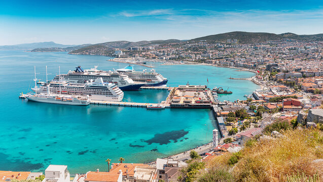 Kusadasi, Turkiye, showing a bustling Aegean Sea port with large cruise ships docked, surrounded by the coastal city and mountains