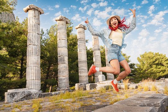 Happy woman exploring ancient Roman ruins, expressing freedom and excitement during travel to a historical archaeological site