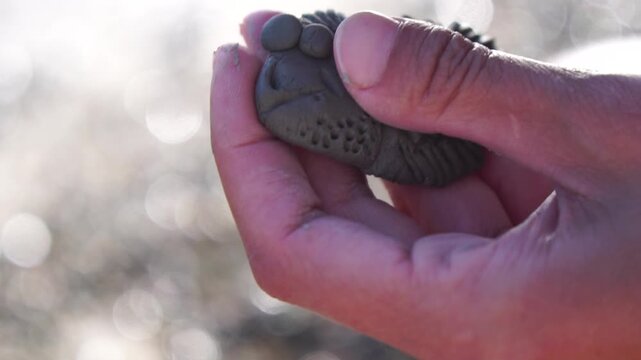 Clay, Hands, Crafting a person's hands are carefully sculpting a small, dark clay figure, showcasing creativity and a hobby