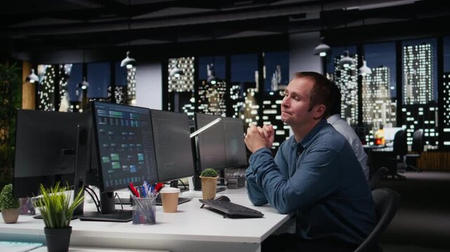 Stressed developer in office coding on computer pleased after developing machine learning model with coding and programming workflow.