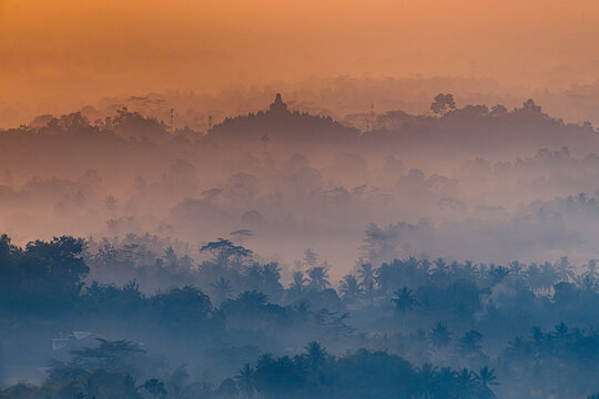 Misty Morning view of Borobudur with layers of trees seen from Setumbu, Indonesia