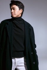 Obraz premium Stylish young man in black outfit exudes confidence in studio space.