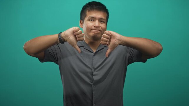 Man showing both thumbs down with visible wristwatch and neutral face in studio; disapproval doubt resignation.
