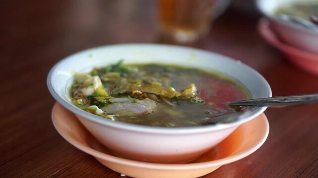 A warm and delicious bowl of traditional Indonesian chicken soup (Soto Ayam) with shredded chicken, cabbage, and fresh green onion topping.