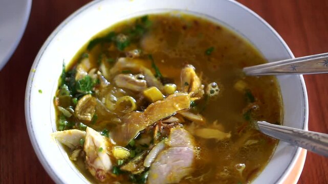 A warm and delicious bowl of traditional Indonesian chicken soup (Soto Ayam) with shredded chicken, cabbage, and fresh green onion topping.