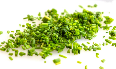 Obraz premium Close-up of finely chopped fresh green chives scattered on a clean white cutting board