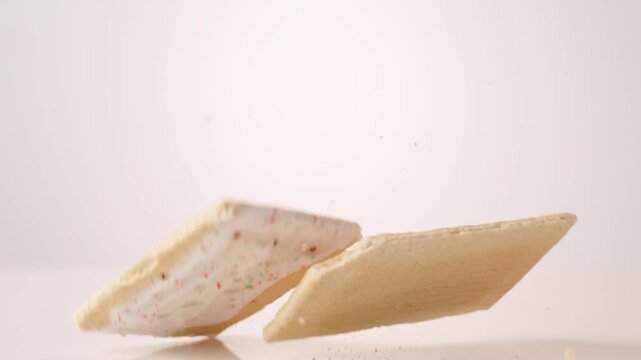Pink frosted retro pop tarts dropping and bouncing across white seamless backdrop in high speed slow motion. back to school posts, after school snack videos, kids brand commercials.