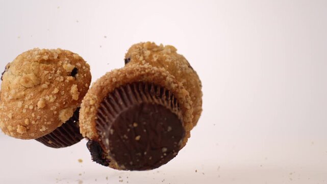 Berry-studded golden muffins bouncing and tumbling on white in slow motion macro studio shot. bakery storefront ads, coffee shop pastry case content, brunch menu reels.