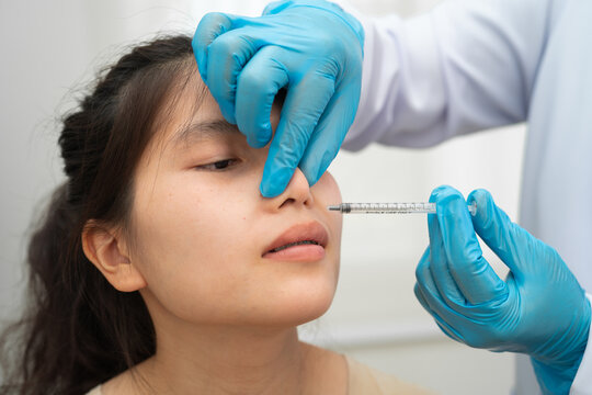 Asian woman receiving plastic surgery shape of nose performed on face.