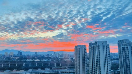 Stunning sunset sky with colorful clouds over modern city skyline, urban architectural landscape background © Jianbo