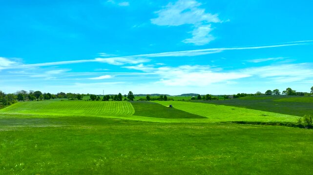 An aerial shot of vibrant green agricultural fields and meadows in Poland under a bright blue sky, perfect for sustainability and nature concepts.