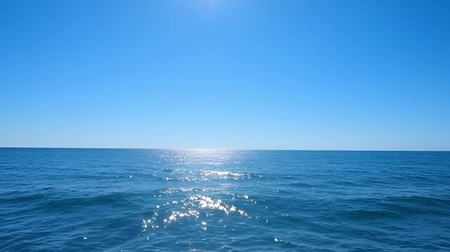 Ocean expanse under a clear blue sky horizon and bright sunlight