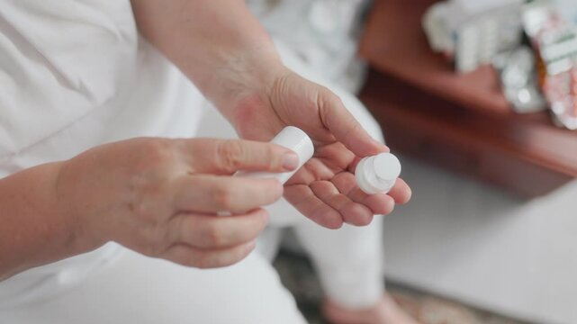 Top view of senior hands pouring brown round pills into an open palm.