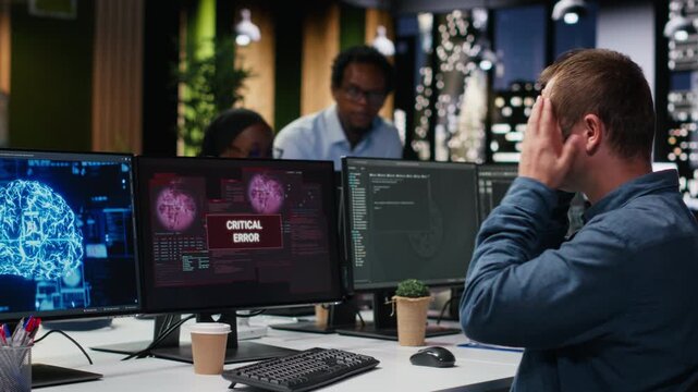 Software developer in office receiving critical error warning while writing code. Tech startup employee using PC to troubleshoot software glitches, resolving system crashes for coding workflows.