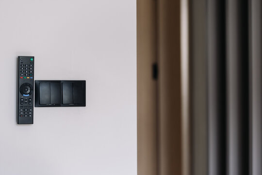 Modern apartment wall with black remote control and multiple light swi