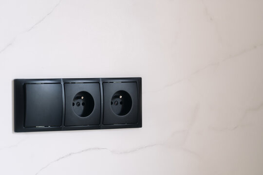 Modern minimalist black electric sockets and switch on a white wall