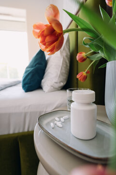 Prescription medication on a table next to a flower vase in a bright room