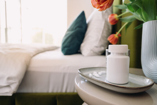 Pill bottle and medication on table in a bedroom during morning routine