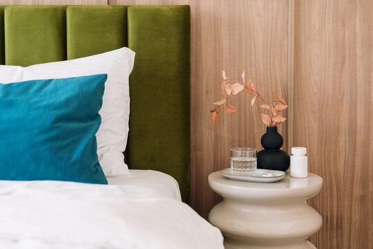 Pill bottle on table with prescription medicine and glass of water in bedroom