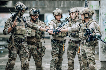 Fototapeta premium Tactical team celebrates mission success raising helmets and fists together in abandoned building