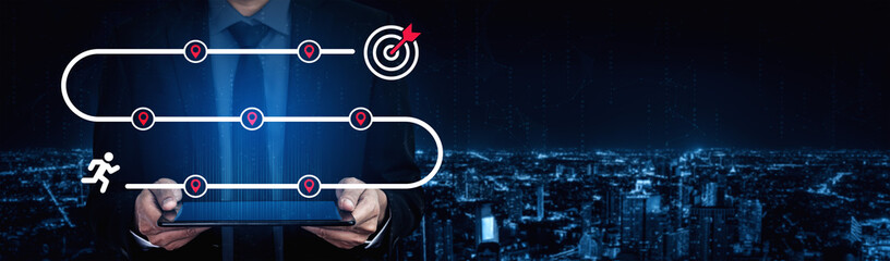 A businessman stands in a cityscape at night, holding a tablet displaying a path with target icons, symbolizing strategy and success in the business world. Ledger © InfiniteFlow