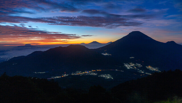 Beautiful Sunrise over Volcanic Mountains and Valley Village Lights, Indonesia