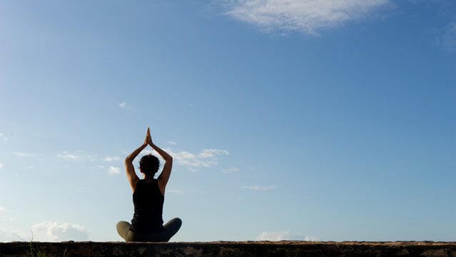 Rear View of Woman Practicing Yoga and Meditation Under a Clear Blue Sky