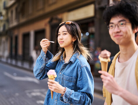 Portrait of a smiling couple in the city, tourists visiting destination, summer trip exploring and eating an ice cream