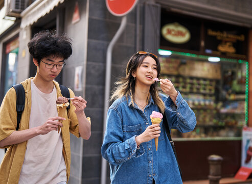 Portrait of a smiling couple in the city, tourists visiting destination, summer trip exploring and eating an ice cream