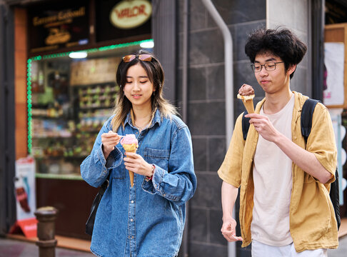 Portrait of a smiling couple in the city, tourists visiting destination, summer trip exploring and eating an ice cream