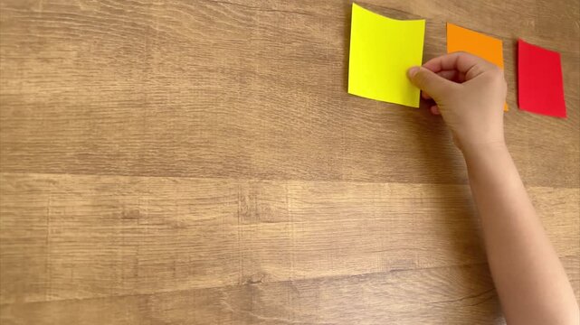 Child Hand Placing a Third Small Origami Paper in a Neat Row, Oblique Overhead View, 4K Silent Video