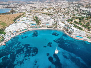 Obraz premium Bodrum peninsula showing a luxury resort, coastline hotels, and a yacht sailing in the clear turquoise waters of the Aegean Sea