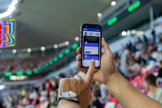 MINSK, BELARUS JUNE 9, 2026: Man holding a purple Apple iPhone 14 Pro in the stadium. The official FIFA website selling tickets for the 2026 FIFA World Cup in the USA, Mexico, Canada.